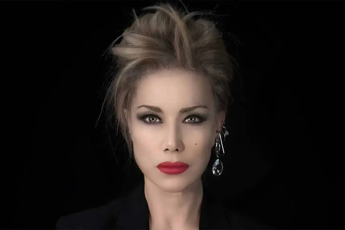 Nancy Brilli con un look audace, labbra rosse e capelli raccolti.