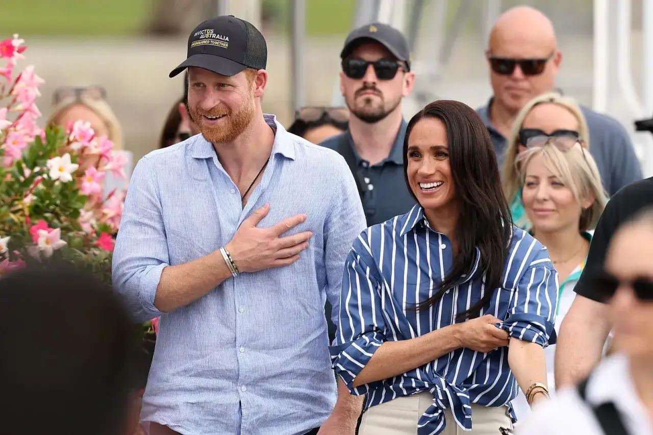 Meghan, Duchessa di Sussex, sorride con gioia accanto al Principe Harry, che indossa un cappellino Invictus Australia.