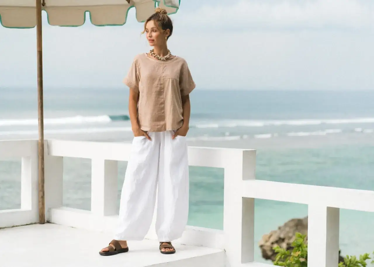 Donna con pantaloni di lino bianchi ampi e maglia beige, perfetta per l'estate. Ecco come abbinarli per un look casual chic.