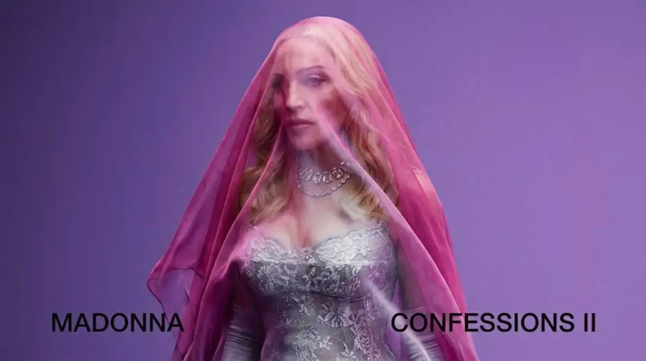 Madonna oggi, velata di rosa, con un abito di pizzo e un collier scintillante.