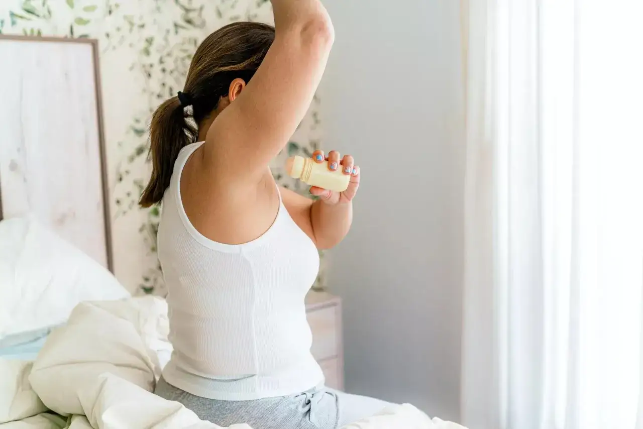 Donna applica deodorante per combattere il sudore puzzolente.