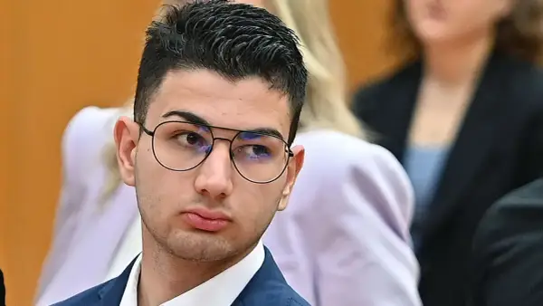 Alex Cotoia, con occhiali e abito blu, ascolta attentamente in tribunale.