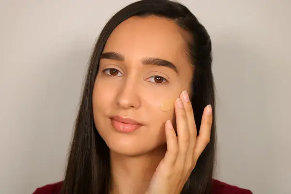 Donna applica fondotinta per definire la mascella, creando un look impeccabile.