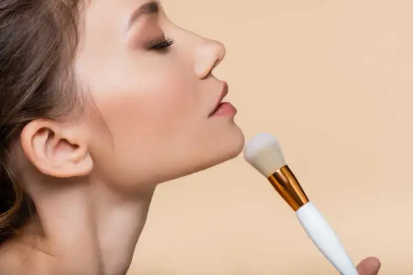 Donna applica cipria con un pennello morbido, un gesto elegante per un look impeccabile.