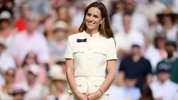 Kate Middleton sorride a Wimbledon, un'icona di stile in un abito chiaro, mentre il pubblico fa da sfondo sfocato.