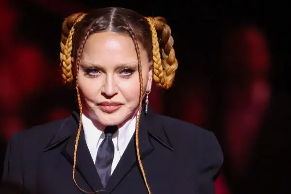 Madonna con trecce bionde e abito scuro, un look iconico per il suo compleanno.