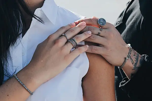 Mani con anelli che esplorano il significato anelli dita. Un bracciale e un anello con bussola completano il look.