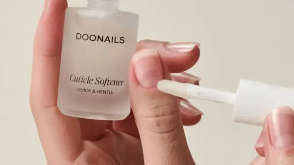 Mani curate con unghie lunghe e sane, applicando un prodotto per ammorbidire le cuticole.