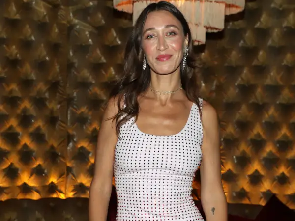 Alana Hadid indossa un abito bianco tempestato di cristalli, con un choker scintillante e orecchini pendenti.