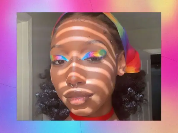 Make up pride: un volto con un trucco arcobaleno sugli occhi e una fascia colorata.