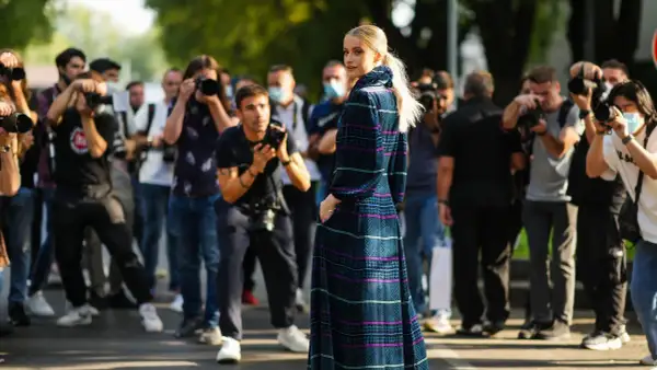 Modella con abito lungo a fantasia, circondata da fotografi. Un'anteprima della fashion week milano 2026.