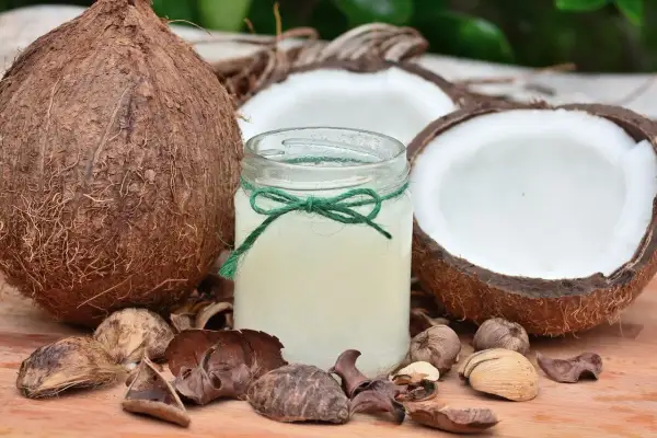 Un barattolo di olio di cocco, circondato da noci di cocco e gusci, pronto a rivelare i suoi benefici.