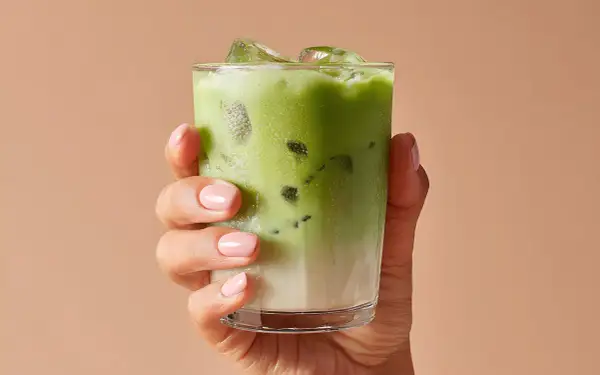 Mano con un bicchiere di matcha ghiacciato. Attenzione alle matcha controindicazioni per goderselo al meglio.
